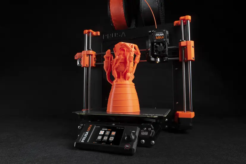 An Original Prusa MK4 3D printer with an orange display print on its build plate.
